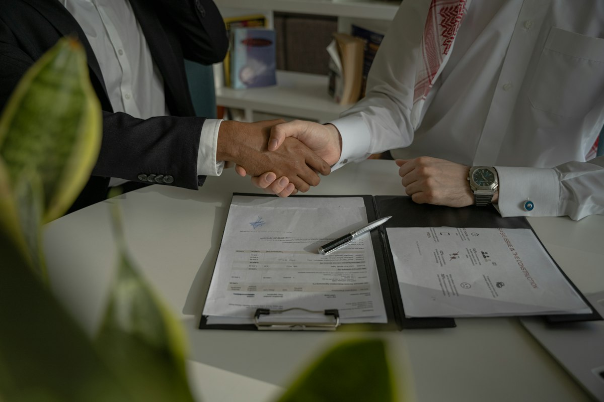 Hai người bắt tay nhau trên một tờ giấy hợp đồng