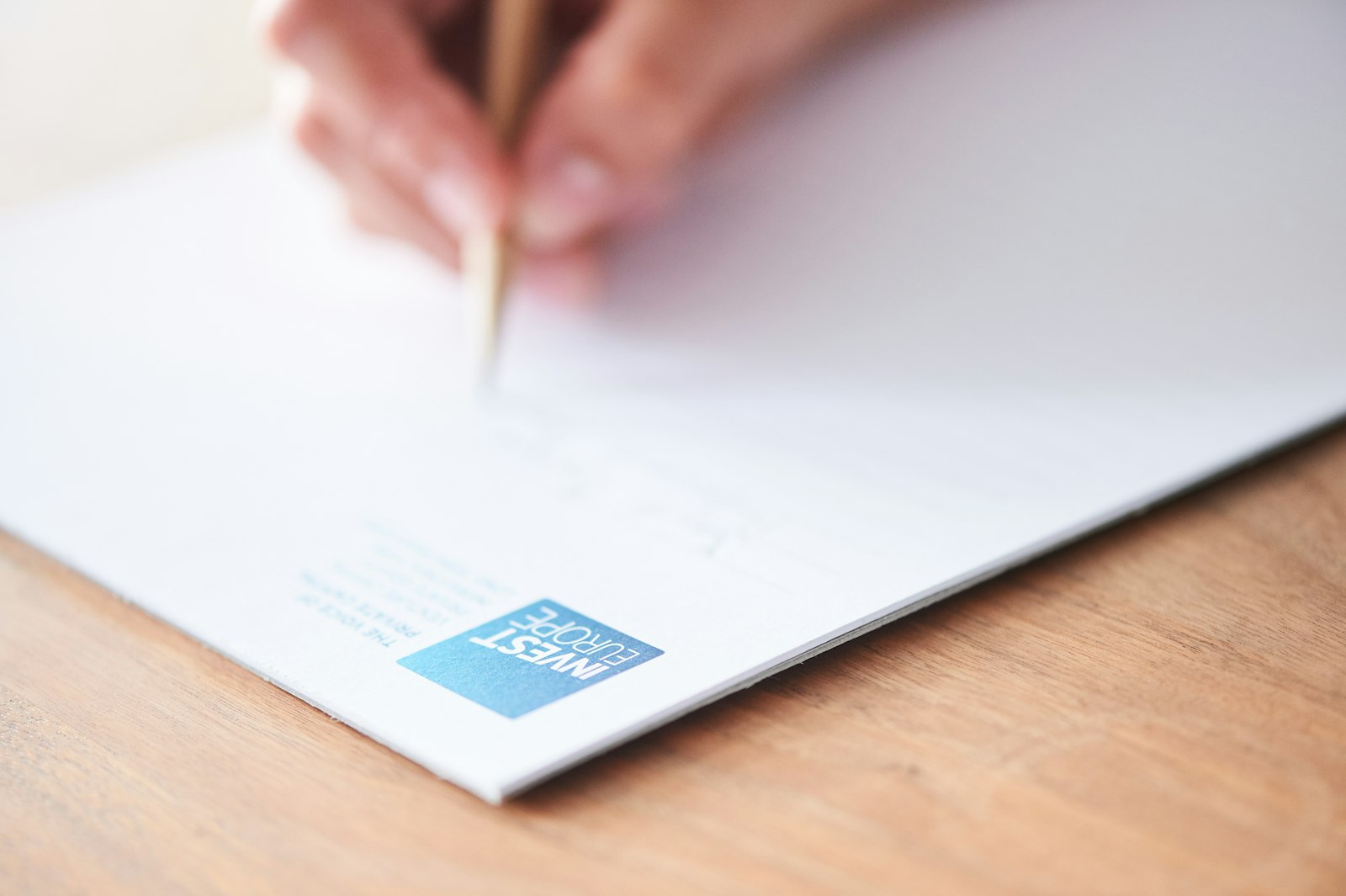 Bàn tay viết thư trên giấy có in logo